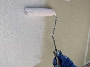 ベージュの外壁に白い下塗り塗料を塗り重ねられていく瞬間
