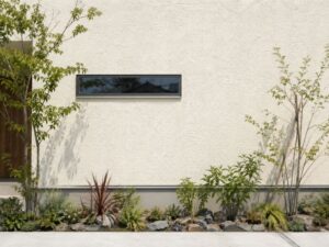 オフホワイトの外壁とナチュラル植栽の外構